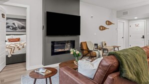 Uma sala de estar moderna com lareira, sofá de couro e televisão de tela plana na parede.