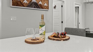 Uma mesa de jantar com uma garrafa de vinho branco, duas taças e um prato de donuts.