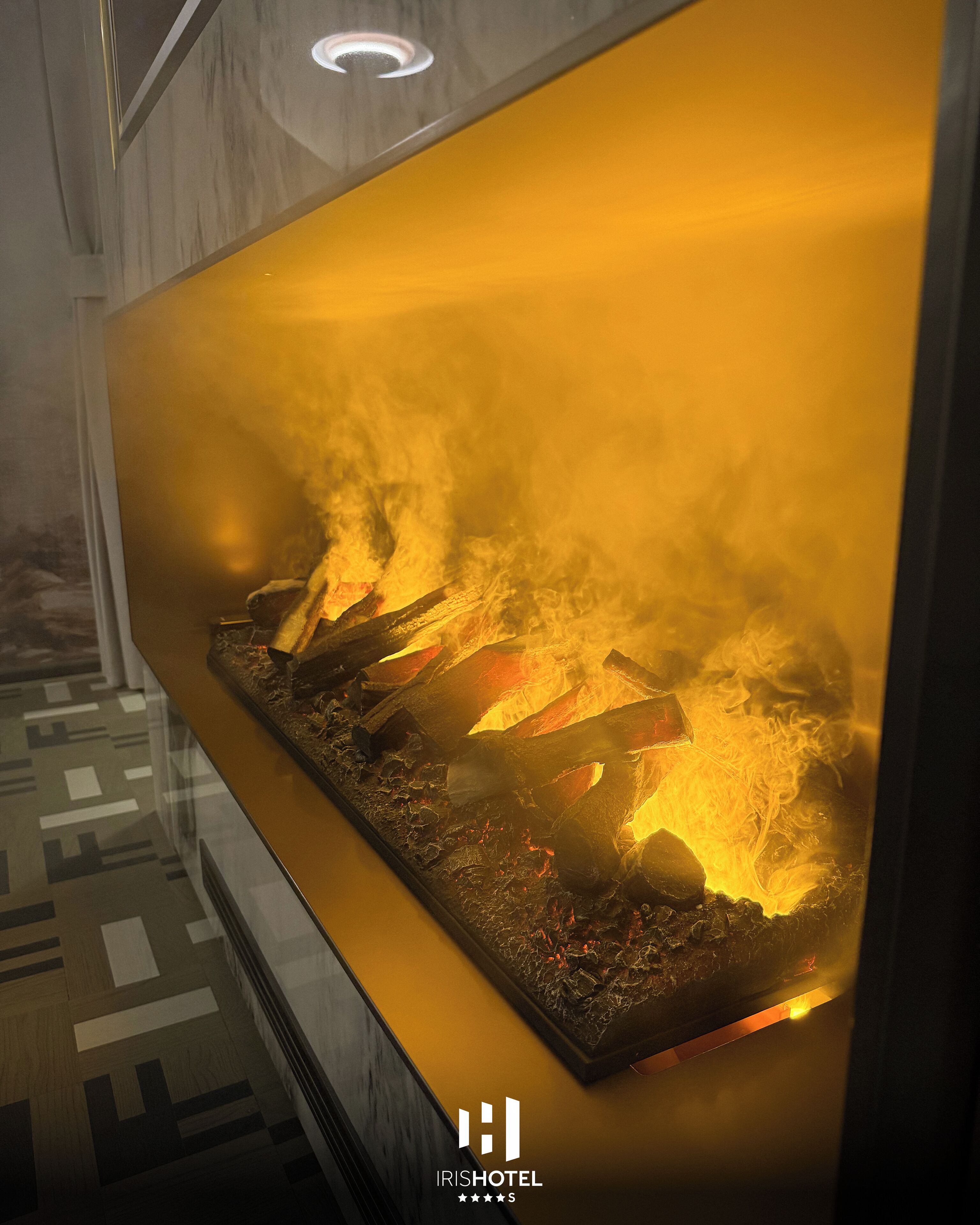 A modern interior with a large, illuminated fireplace displaying burning logs and flames.