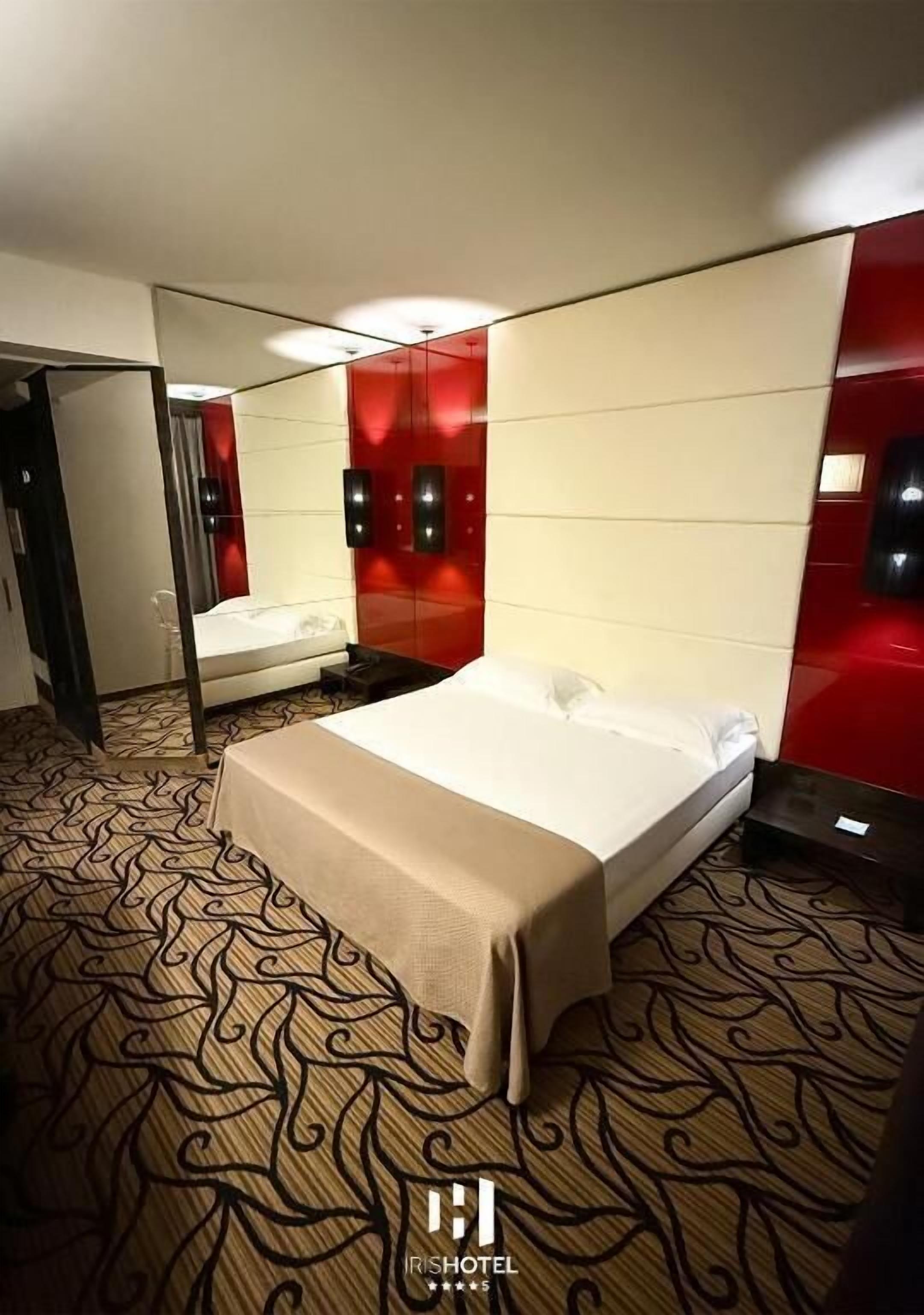 Ein Hotelzimmer mit einem Bett, einem Spiegel und einem gemusterten Teppich.