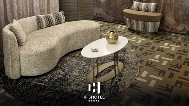 Una habitación de hotel moderna con un sofá curvo, una pequeña mesa redonda y un espejo decorativo.