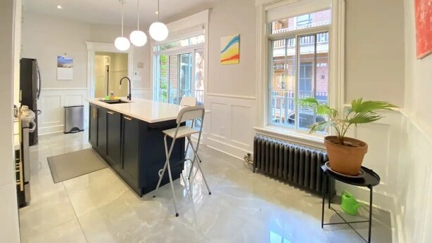 A modern kitchen with a central island, pendant lighting, and a view of the street through large windows. - 2-bedroom large impeccable apartment in fabulous Montréal. (Montréal)