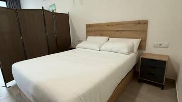 A bedroom with a wooden bed, a nightstand, a wardrobe, and a ceiling light.