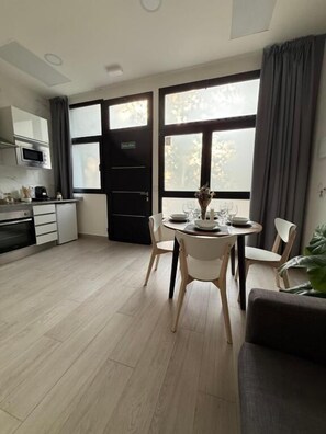 A modern kitchen with a dining area, large windows, and a view of trees. - APARTAMENTOS CIUDAD DE LAS ARTES  (València)