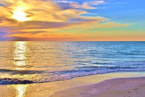 Uma praia com um pôr do sol sobre o oceano.
