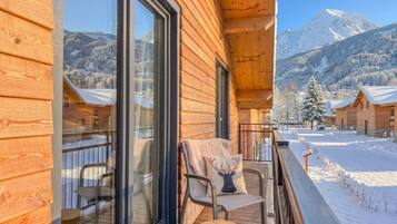 A wooden cabin with a balcony overlooking a snowy mountain landscape.