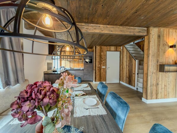 A dining area with a wooden table, chairs, and a hanging light fixture.