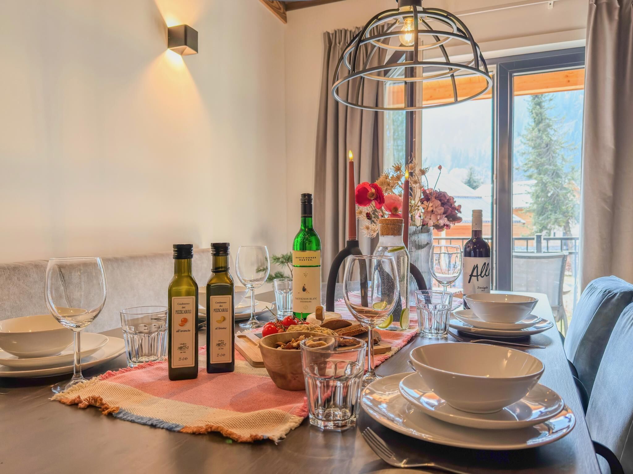 Une table à manger dressée avec des bouteilles de vin, des verres et un vase rempli de fleurs.