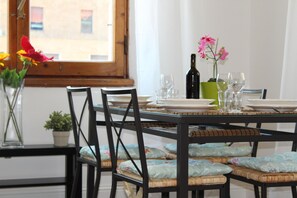 A dining table set with plates, glasses, and a bottle, surrounded by wicker chairs with cushions. - SMN Family Apartments - In front of SMN Station up to 10 guests (Firenze)