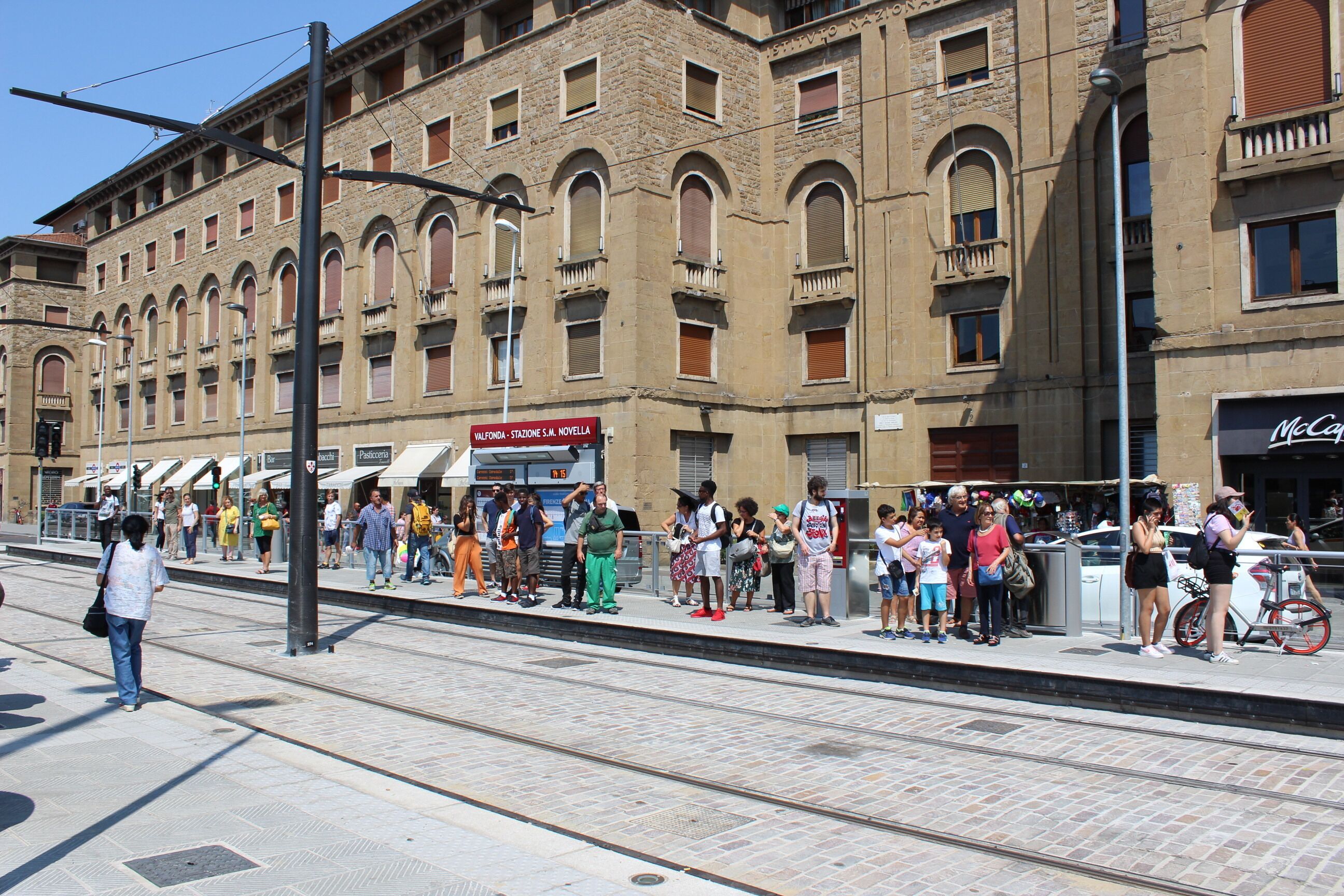 A train station platform with a crowd of people waiting.