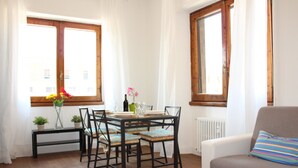 Ein Essbereich mit Tisch für vier Personen, umgeben von Stühlen, in der Nähe eines Fensters mit Vorhängen.