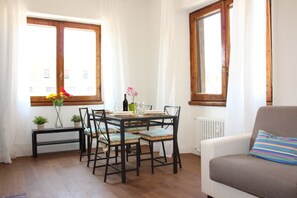 A dining area with a table set for four, surrounded by chairs, near a window with curtains. - SMN Family Apartments - In front of SMN Station up to 10 guests (Firenze)