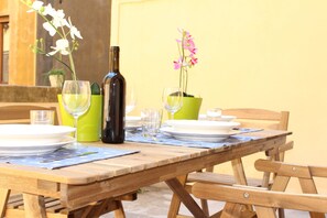A wooden dining table set with plates, glasses, and a bottle, accompanied by potted orchids. - SMN Family Apartments - In front of SMN Station up to 10 guests (Firenze)