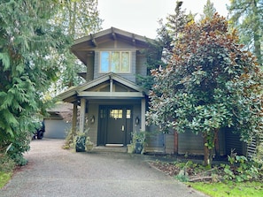 A two-story house with a front porch, a driveway, and a mailbox. - Fern Hollow - unwind in this nature inspired suite in Edgemont Village. (North Vancouver)