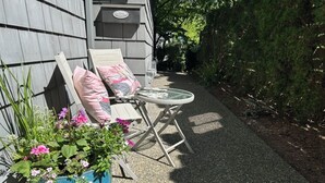A patio with a chair, a small table, and a potted plant. - Fern Hollow - unwind in this nature inspired suite in Edgemont Village. (North Vancouver)