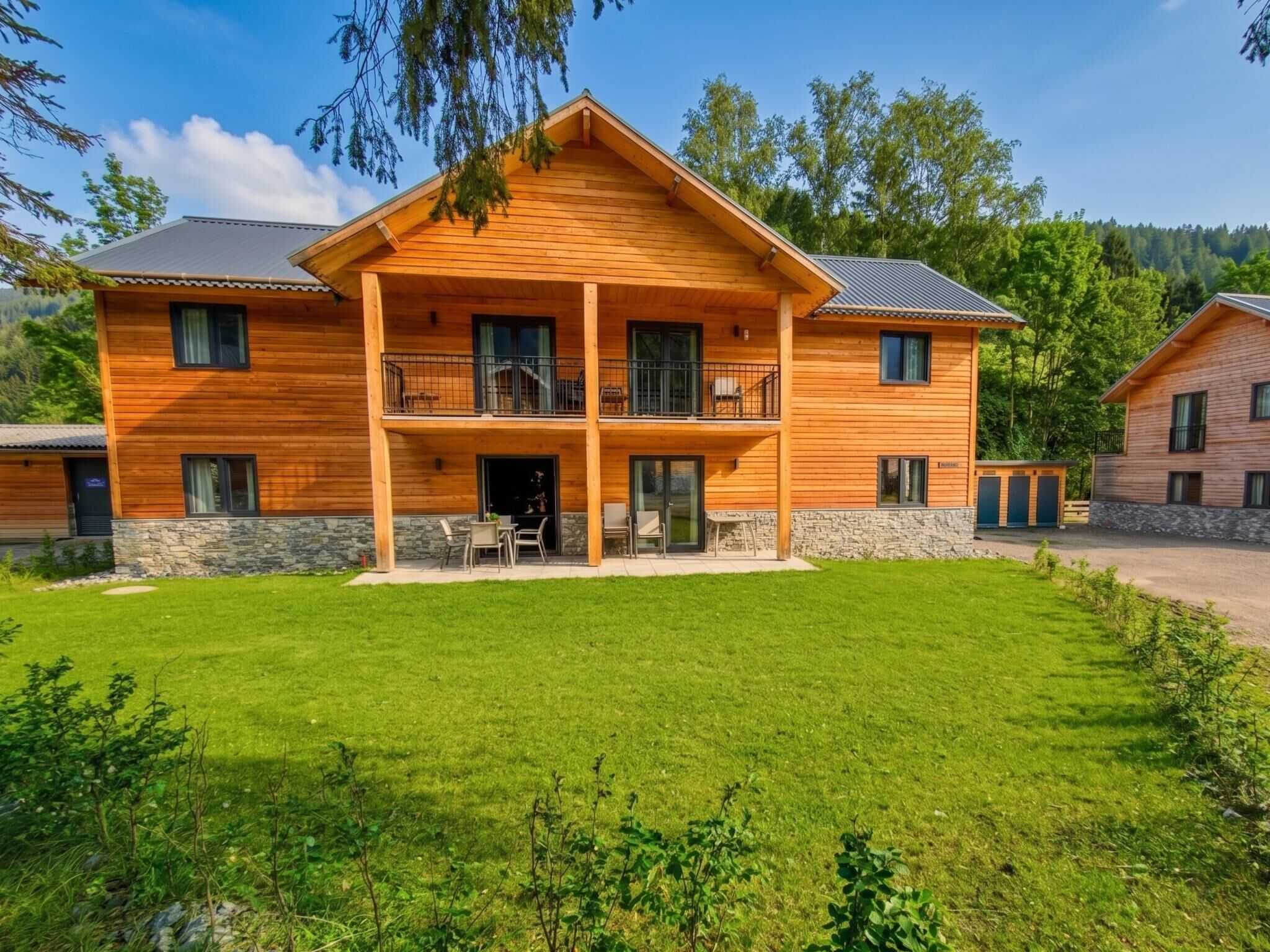 Een houten huis met twee verdiepingen, een balkon, een stenen fundering en een verzorgd gazon.