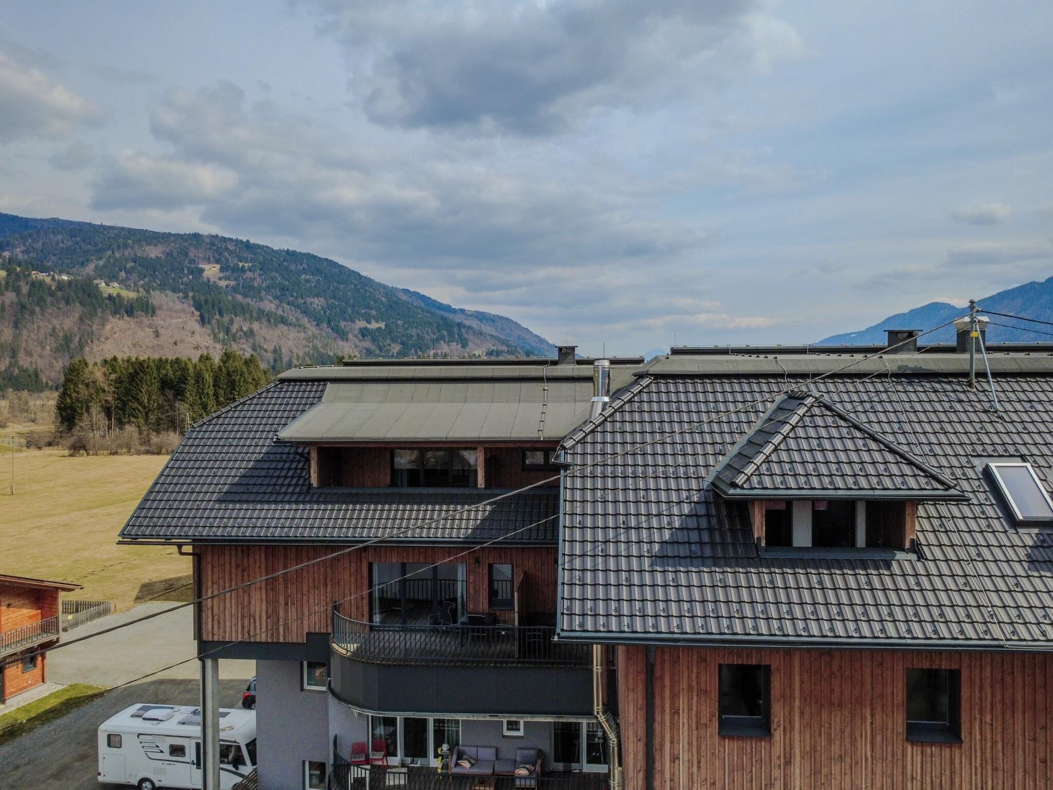 Un bâtiment à deux étages, doté d’un toit en pente, d’un balcon à l’étage supérieur et d’un garage visible où se trouve un camping-car.