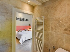 Un baño con lavamanos blanco, toallero y zona de ducha.