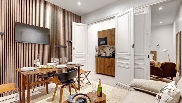 Een moderne woonkamer met een eetgedeelte, keuken en slaapkamer.