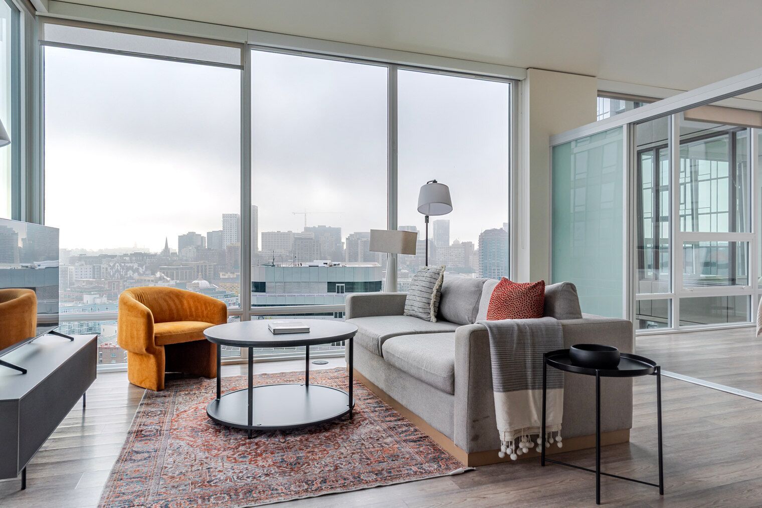 Una sala de estar moderna con vistas a la ciudad, un sofá, una mesa de centro y una silla.