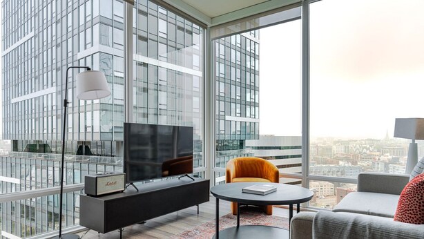 Een moderne woonkamer met een grote televisie, een bank, een fauteuil en een bijzettafeltje.
