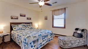Ein Schlafzimmer mit Bett, Sessel, Deckenventilator und Wandbildern.