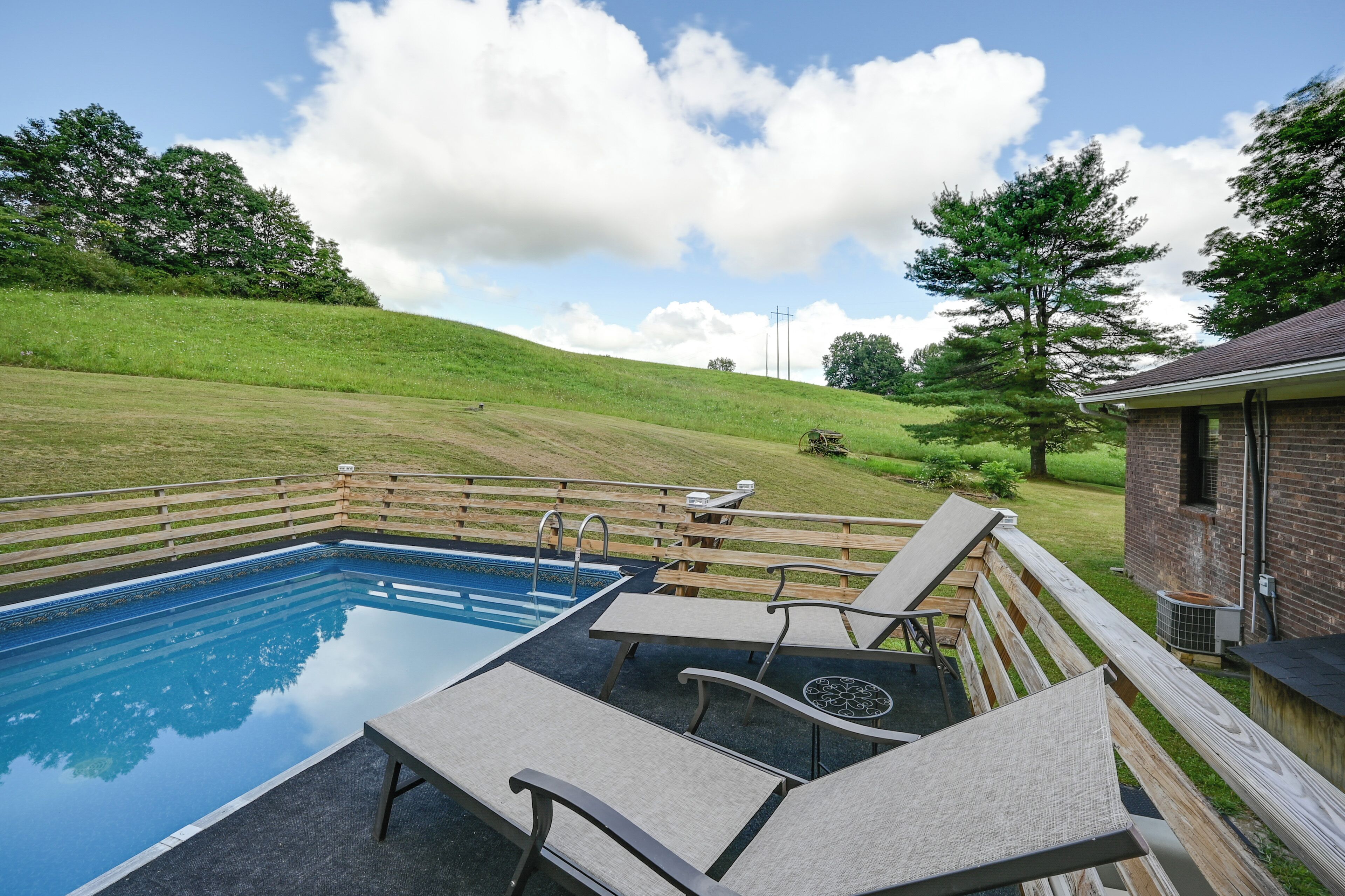 Une piscine avec des chaises longues et une terrasse en bois.