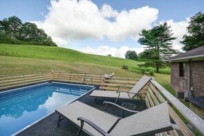 Una piscina con sillones de descanso y una terraza de madera.