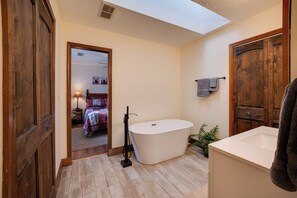 Ein modernes Badezimmer mit freistehender Badewanne, Holztüren und einem Oberlicht.