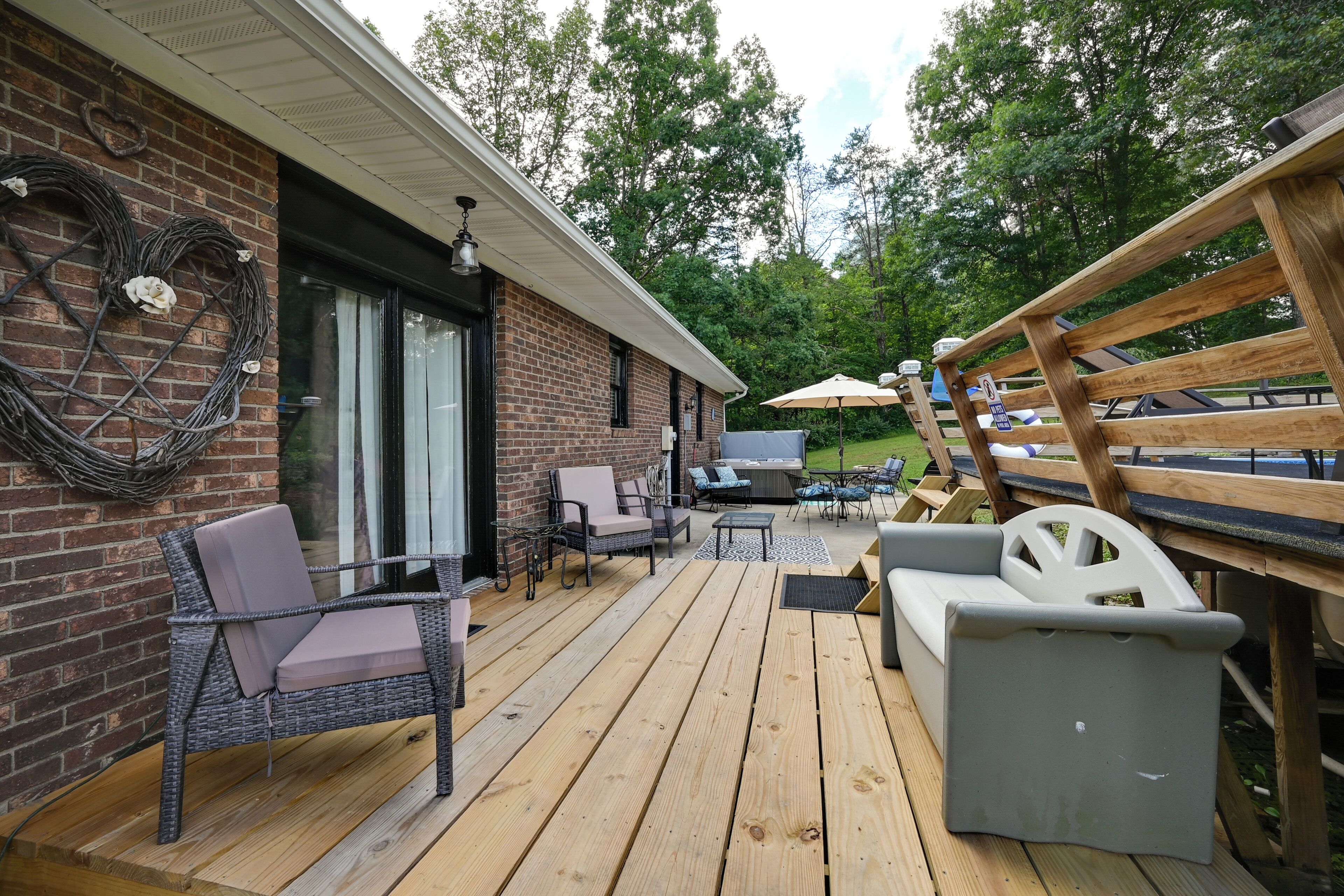 A covered outdoor patio with wicker furniture, a grill, and a wooden deck.