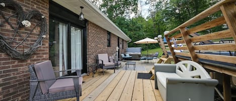 Un patio techado al aire libre con mobiliario de mimbre, una parrilla y una terraza de madera.
