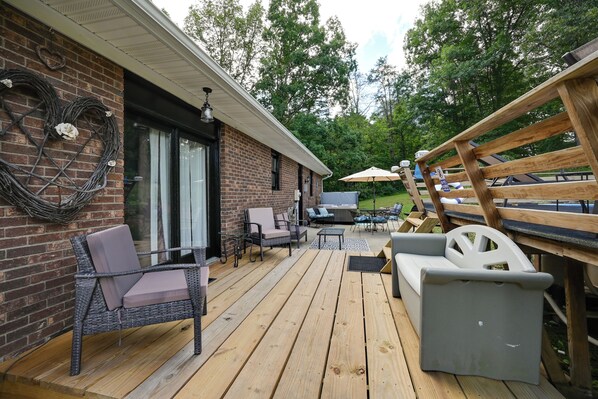 Un patio techado al aire libre con mobiliario de mimbre, una parrilla y una terraza de madera.