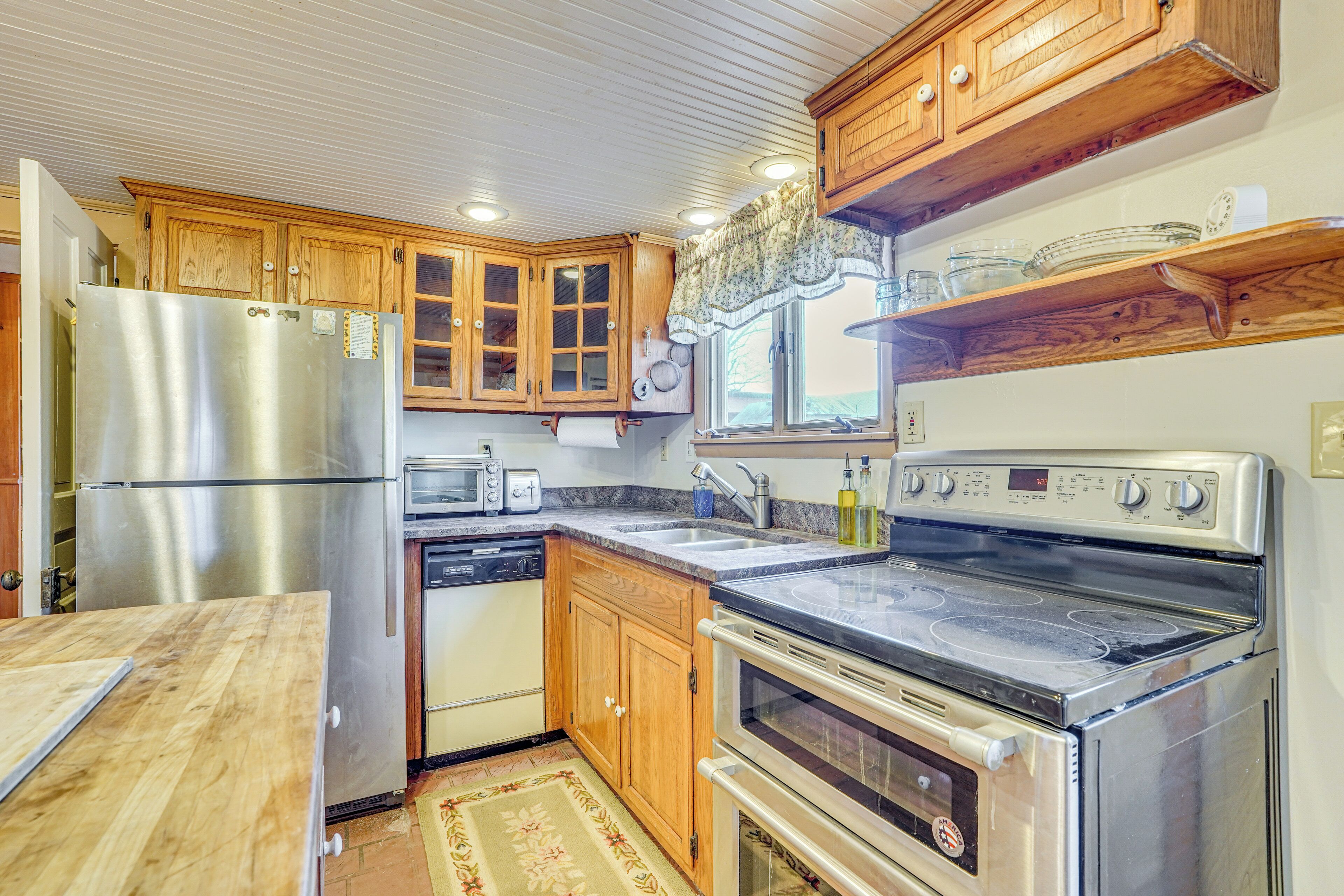 A kitchen with wooden cabinets, stainless steel appliances, and a window above the sink.