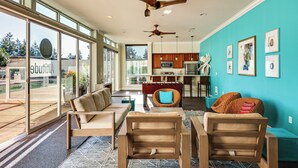 A spacious living area with a sofa set, a coffee table, and a dining table. There are ceiling fans, a kitchen area with a microwave, and a large window offering a view of the outdoors. - 4 Mi to Dtwn, Commuter-Friendly Apt in Tacoma (Tacoma)