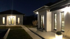 Ein modernes, zweistöckiges Haus mit einer gut beleuchteten Eingangsparte und einem kleinen Garten.