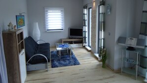 Ein modernes Wohnzimmer mit einer Couch, einem Fernseher, einem kleinen Tisch und einem blauen Teppich.