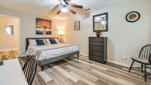 A bedroom with a bed, a dresser, a chair, a ceiling fan, and a painting on the wall. - Cozy Family Retreat! Home in Charlotte Suburbs (Charlotte)