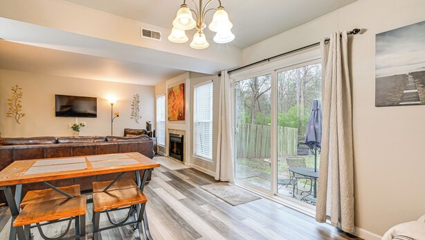 A spacious living room with a fireplace, a large dining table, and a sliding glass door leading to a patio. - Cozy Family Retreat! Home in Charlotte Suburbs (Charlotte)
