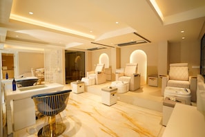 A modern spa room with a massage chair, a foot bath, and a large mirror. - Kings Mansion (Candolim)