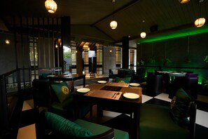 A restaurant with a checkered floor, green upholstered chairs, and hanging pendant lights. - Kings Mansion (Candolim)