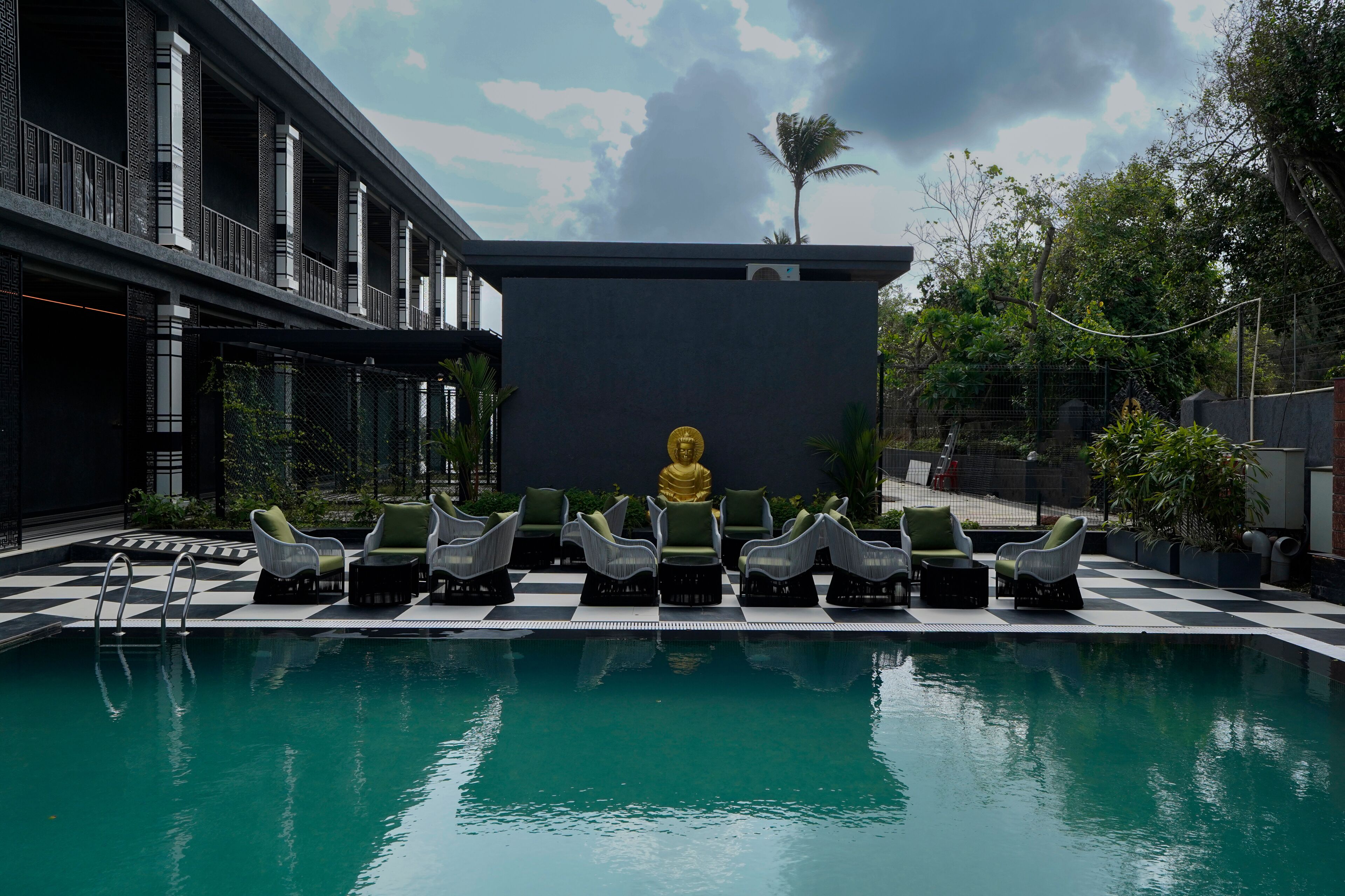Zona de piscina con sillones de descanso y una estatua de Buda.