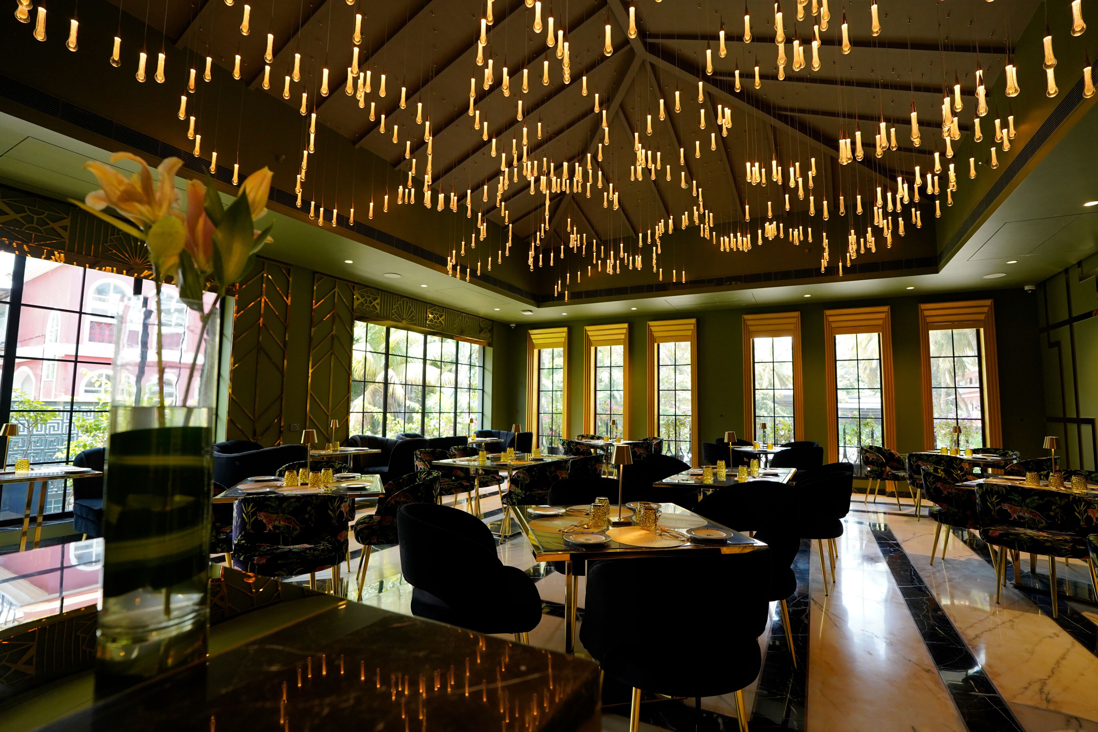 A restaurant interior with multiple tables, chairs, and hanging light fixtures.