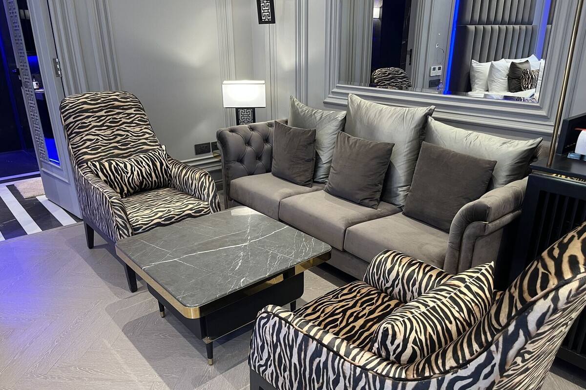 Ein modernes Wohnzimmer mit einer Couch, zwei Sesseln, einem Couchtisch und einer Lampe.