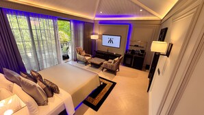A hotel room with a bed, two chairs, a TV, and a desk. - Kings Mansion (Candolim)