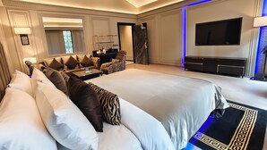 A hotel room with a large bed, a sofa, a TV, and a minibar. - Kings Mansion (Candolim)