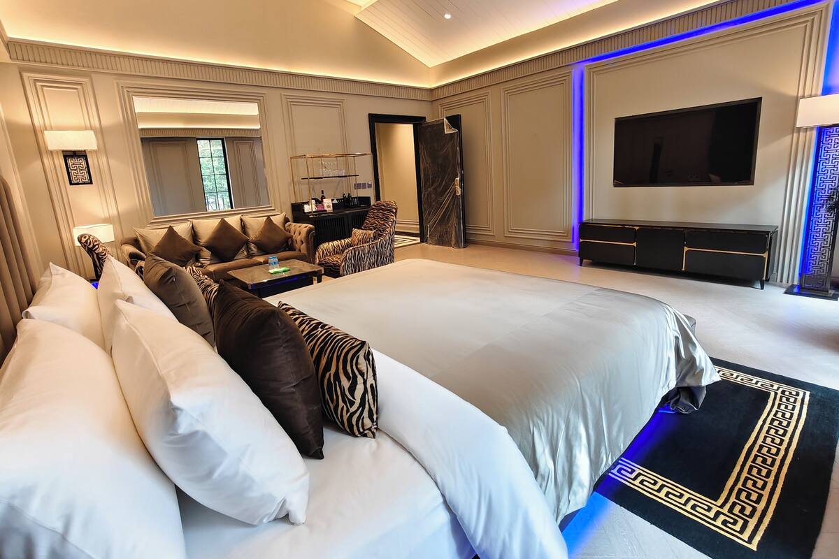 Ein Hotelzimmer mit einem großen Bett, einer Sitzecke, einem Fernseher und einer Minibar.