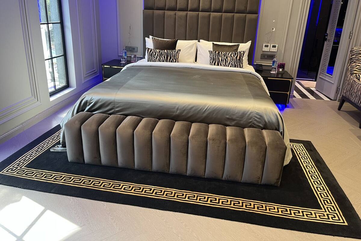 Ein modernes Schlafzimmer mit einem großen Bett, einer Kopfteil und einem dekorativen Teppich.