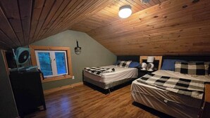 Ein gemütliches Schlafzimmer im Dachgeschoss mit zwei Betten, einem Fenster mit Aussicht und einem Deckenventilator.