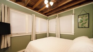 Una camera da letto con un letto, una ventola a soffitto e una TV a parete.