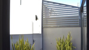 Ein moderner Balkon mit zwei Blumentöpfen, einem Metallgeländer und Blick zum Himmel.